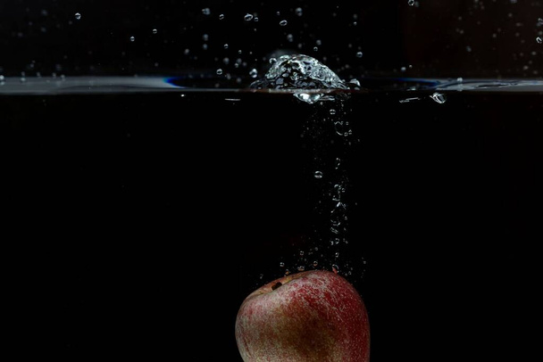 Bella vista di mela colorata che cade in acqua su sfondo nero. Sfondi meravigliosi
. - Foto, immagini