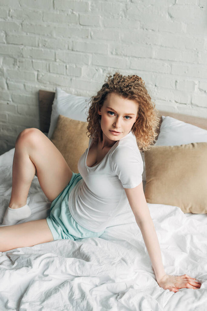 attractive young woman in homewear sitting on bed in morning   - Photo, image