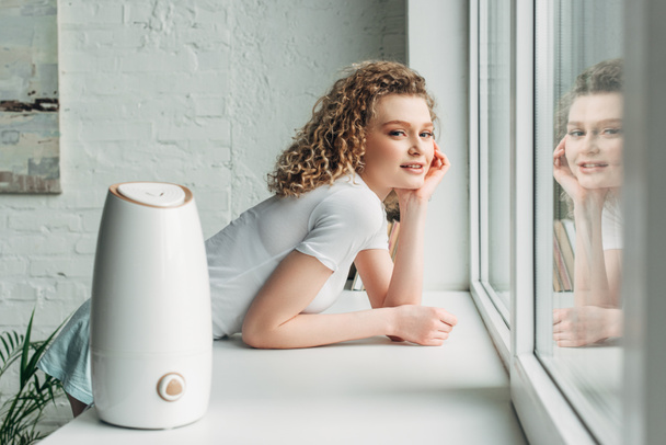 smiling girl with ultrasonic air purifier on windowsill - Photo, Image