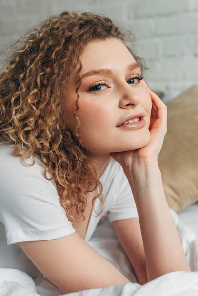 positive attractive curly girl in homewear on bed in morning   - Fotó, kép