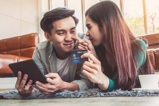 若いカップルは家でインターネットのウェブサイトのオンラインショッピングのためのクレジットカードを使用する。クレジットカードの番号がモックアップされます。クレジットカードに個人情報は表示されません。オンラインショッピングのコンセプト. - 写真・画像