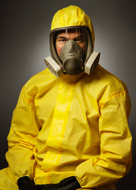 portairt de un hombre soltero con un traje de protección de materiales peligrosos en el estudio sobre un fondo
 - Foto, imagen