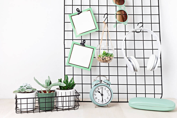 Mockup of mesh board with blank cards, sunglasses, earphones, house plants, alarm clock. Stay home, home organisation, planning concept. - Photo, Image