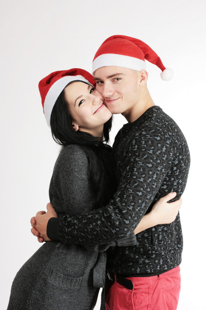 Amar pareja feliz joven en sombreros de Navidad
 - Foto, Imagen
