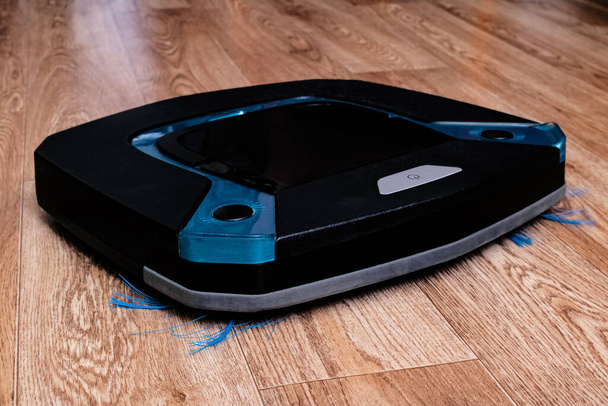 Aspirapolvere robotico nero sul pavimento in legno da vicino
 - Foto, immagini