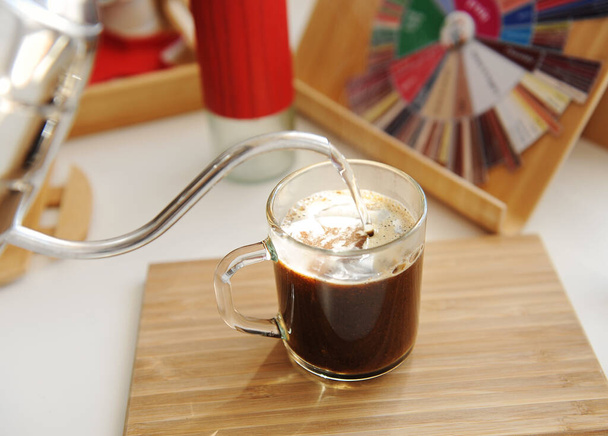 Brassage de café dans une tasse. Verser de l'eau de la bouilloire à col de cygne dans une tasse vitreuse avec du café fraîchement moulu
 - Photo, image