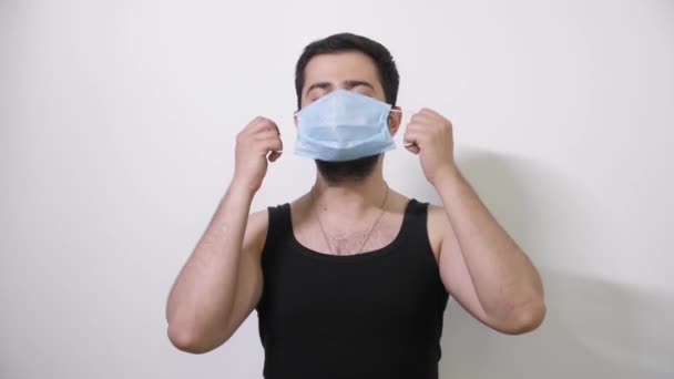 Caucasian man puts on his medical mask looks into camera and shows the stop sign Covid19 Coronavirus - Filmmaterial, Video