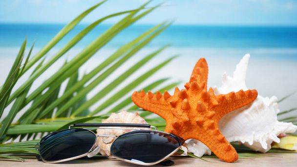 Sunglasses with seashells and blurred beach background summer time concept. - Foto, Imagem