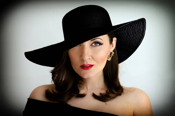 Portrait d'un modèle féminin coiffé d'un chapeau noir sur fond blanc
 - Photo, image