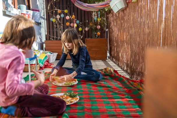 Lapset nauttivat pizzaa parvekkeella piknik
 - Valokuva, kuva