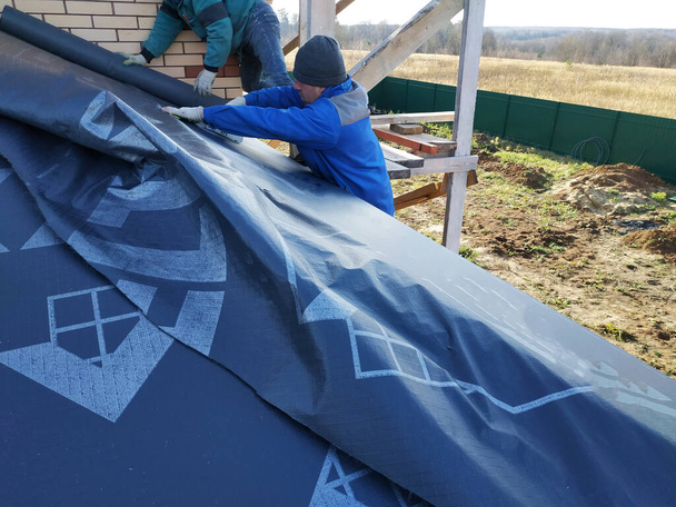 Il tetto è coperto con materiale isolante, la base del tetto. Tavole martellanti dei lavoratori alla base del tetto.2020
 - Foto, immagini