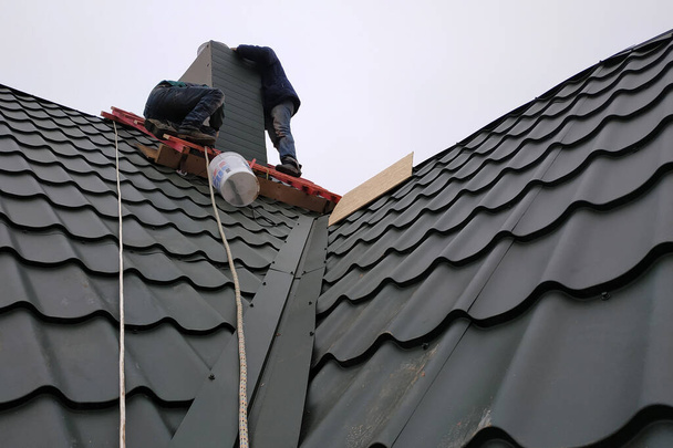 Práce se střešním materiálem, kovovou střechou, ručním šroubovákem.2020 - Fotografie, Obrázek