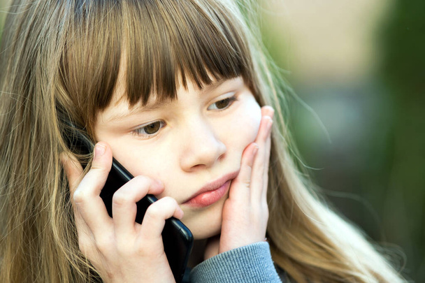 Portrait of stressed child girl with long hair talking on cell phone. Little female kid communicating using smartphone. Children communication concept. - Fotoğraf, Görsel