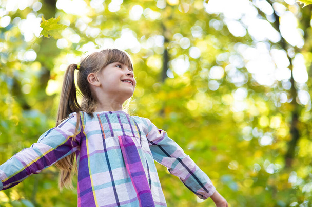 秋の森で楽しい幸せな子供の女の子の肖像画。正の女性の子供楽しい暖かい日で秋の公園. - 写真・画像