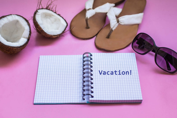 Концепция отпуска и путешествия. Набор для путешествий. Ноутбук с летней обувью, солнечными очками, экзотическим фруктовым кокосом на розовом фоне
.  - Фото, изображение