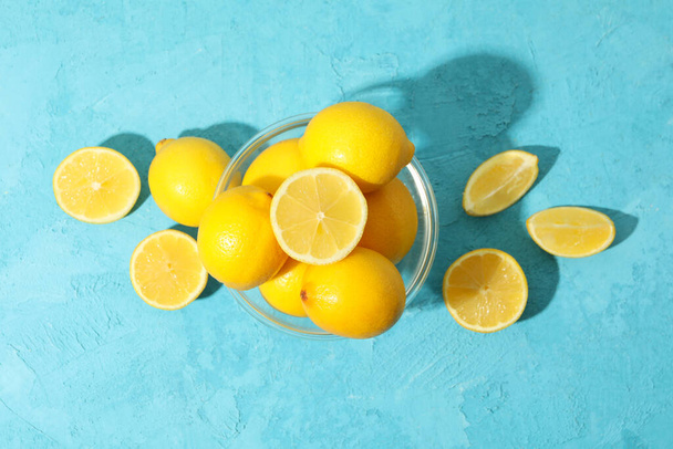 Schale mit Zitronen auf blauem Hintergrund, Ansicht von oben. Reife Früchte - Foto, Bild