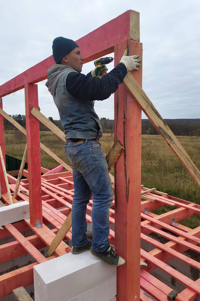 Joiner na instalação do telhado, martelo prego martelo em viga de madeira.2020
 - Foto, Imagem
