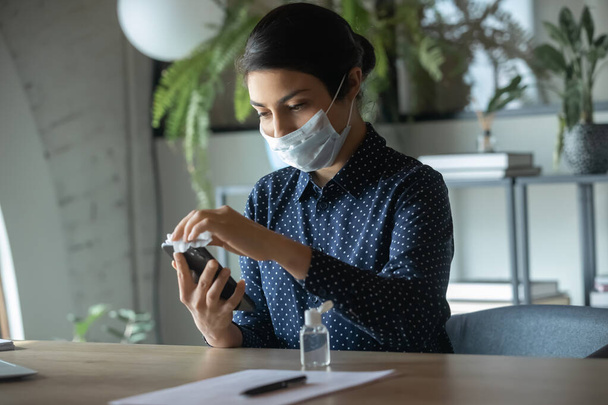 Female in face mask disinfect cellular with sanitizer - Photo, image