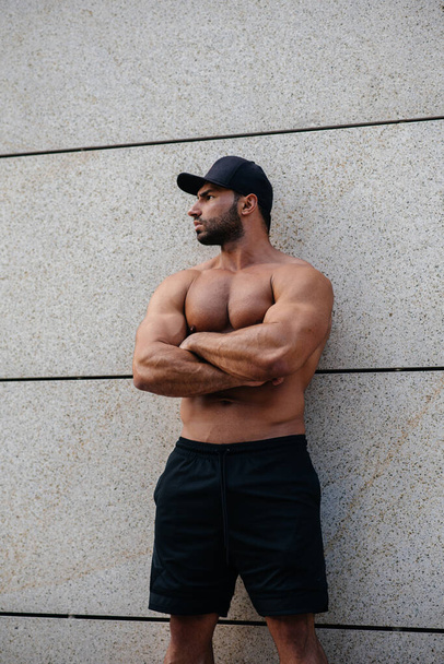 sexy sportsman stands topless near the wall. Fitness, bodybuilding - Fotó, kép