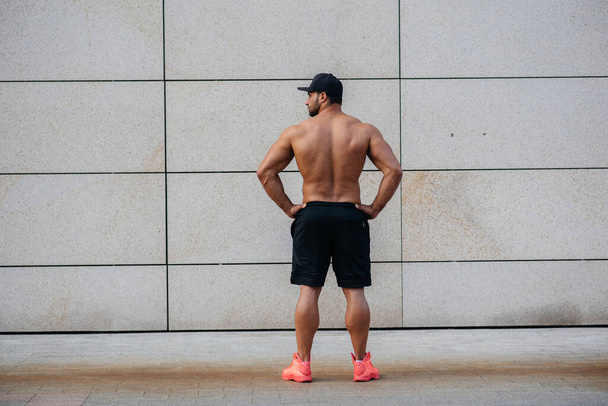 Sexy athlete stands with his back against the wall. Fitness. Healthy lifestyle. - Fotografie, Obrázek