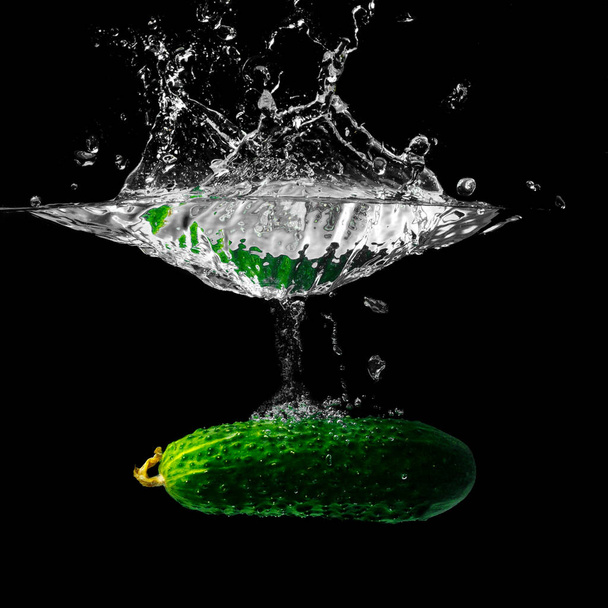 Cucumber in the stream of pure cold water on black background.green cucumber and spray of water - Fotoğraf, Görsel
