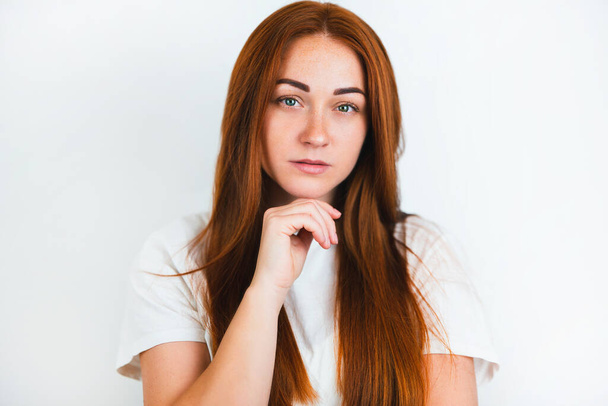 portrait of redheaded young woman looking natural holding hand near her chin on isolated white backgroung, style and beauty concept. - Fotografie, Obrázek
