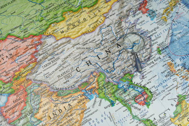 Μεγεθυντικό γυαλί για Wuhan, Κίνα σε έναν παγκόσμιο χάρτη. - Φωτογραφία, εικόνα