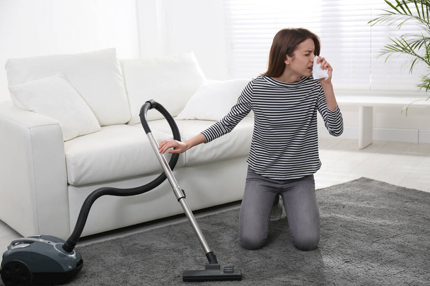 Young woman suffering from dust allergy while vacuuming house - Valokuva, kuva