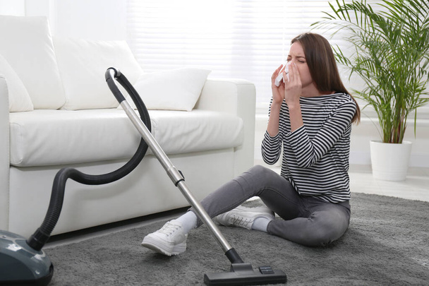Young woman suffering from dust allergy while vacuuming house - Foto, Imagen