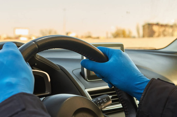 Covid-19 concept. Man drives a car in blue protective medical gloves. Protection from bacteria and viruses. Coronavirus protection. Guarantine and corona disease. Closeup - Foto, Imagem