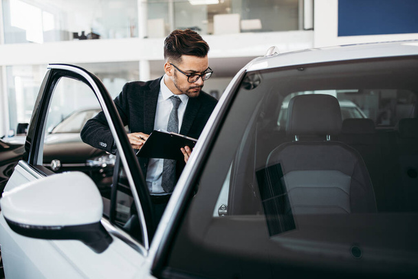 Car seller working in showroom and quality control checking of car details for the last time before buyer comes. - 写真・画像