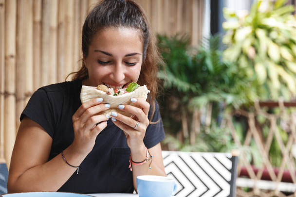 Food, blogging and lifestyle concept. Portrait of cute european woman eating out at cafe during her travelling, tourist trying new cuisine, biting pita, have lunch at hotel restaurant - Valokuva, kuva