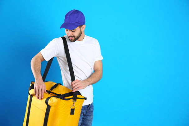 Courier with thermo bag on light blue background, space for text. Food delivery service - Zdjęcie, obraz
