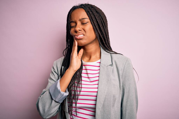 Young african american business woman standing over pink isolated background touching mouth with hand with painful expression because of toothache or dental illness on teeth. Dentist - Foto, Bild