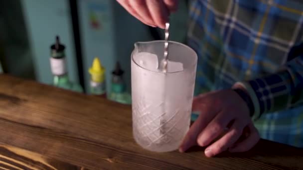 A csapos jeget keverget egy üvegedényben, koktélt készít. - Felvétel, videó