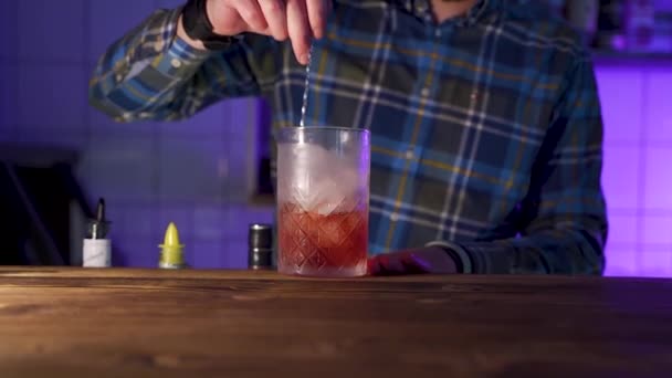 Bartender stirring ice in glass jug, making cocktail, zoom in with going upwards - Filmmaterial, Video