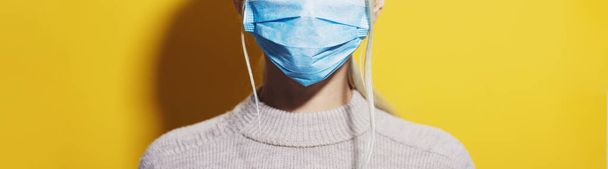 コロナウイルスに対して医療用呼吸器面マスクをしている少女。黄色の背景にパノラマの肖像画. - 写真・画像