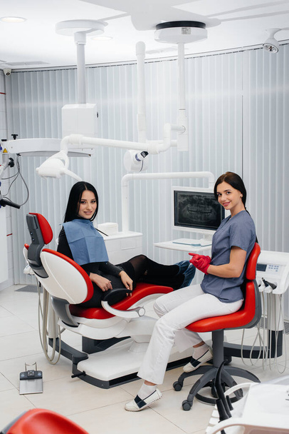 Dentysta pokazuje zdjęcie zębów pacjenta i informuje o niezbędnym leczeniu. Stomatologia, zdrowie. - Zdjęcie, obraz