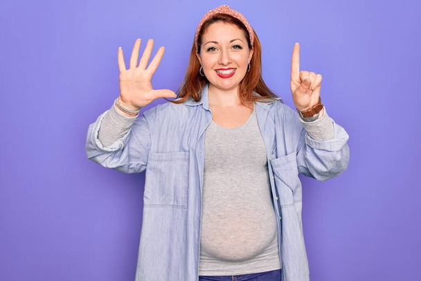 Młoda piękna ruda kobieta w ciąży spodziewa się dziecka nad odizolowanym fioletowym tle pokazując i wskazując palcami numer sześć uśmiechając się pewny siebie i szczęśliwy. - Zdjęcie, obraz