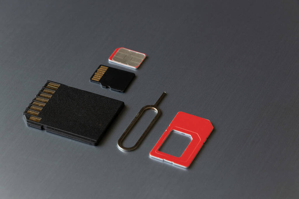 SIM card and paper clip to open the SIM card slot and the memory card are on a gray steel background - Photo, Image