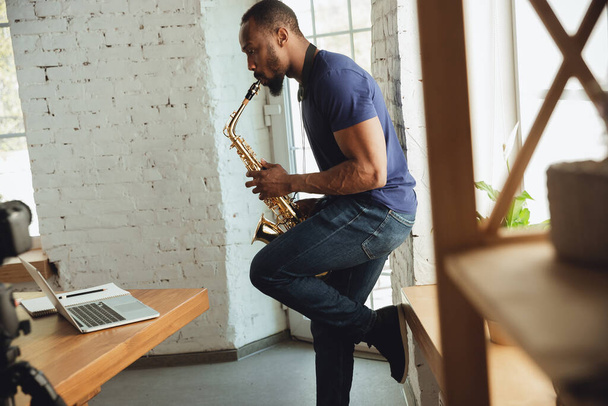 African-american musician playing saxophone during online concert at home isolated and quarantined, impressive improvising - Photo, Image