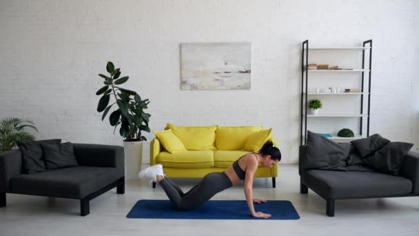 Красивая молодая женщина делает упражнения для живота на ковре в комнате
 - Кадры, видео