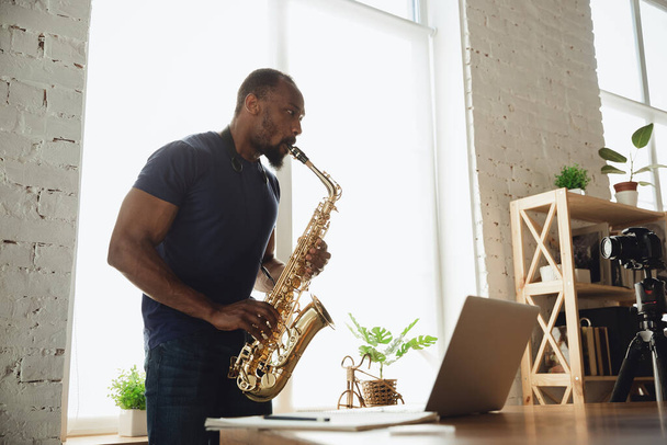African-american musician playing saxophone during online concert at home isolated and quarantined - Photo, Image