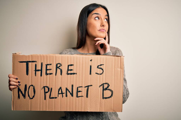 Giovane bella bruna attivista donna protestando per salvare il pianeta tenendo banner faccia seria pensando alla domanda, idea molto confusa
 - Foto, immagini