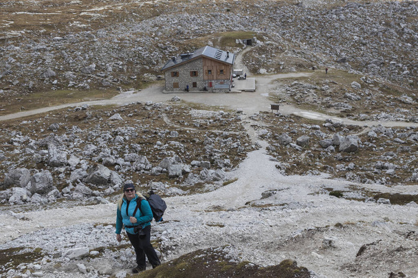 Žena v modré bundě, turista, fotograf na treku kolem Tre Cime Lavaredo v italských Dolomitách, s horami a modrým nebem s mraky v pozadí. - Fotografie, Obrázek