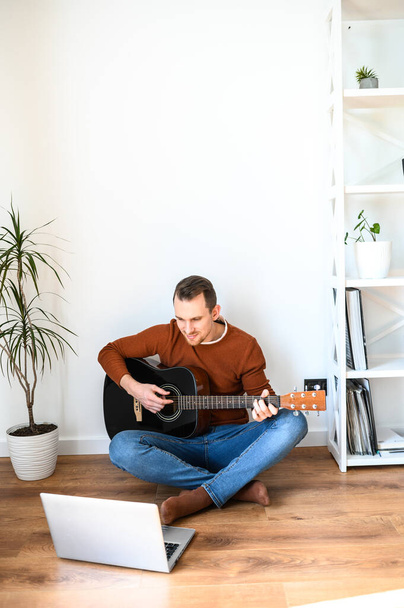 A guy watches video tutorial on guitar playing - Photo, image