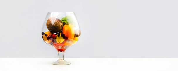 aquarium with healthy food, fruits, vegetables and berries (strawberries, strawberry, raspberry, coconut, broccoli, pepper, orange, lemon) juice juicy on a white background - Photo, image