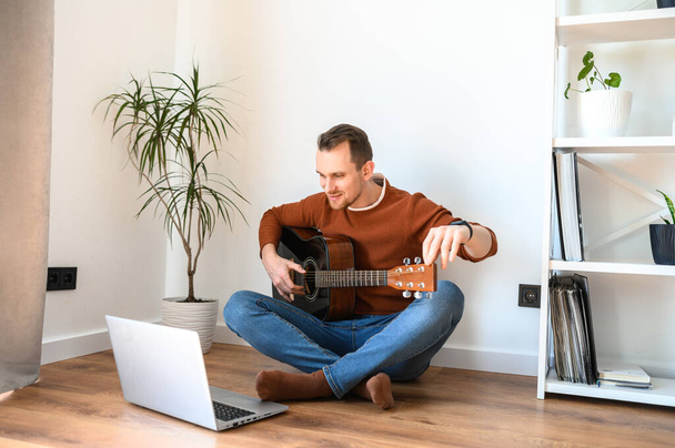 A guy watches video tutorial on guitar playing - Foto, Imagem
