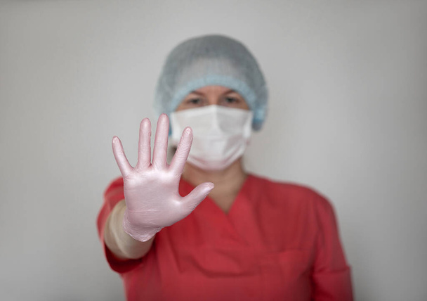 A female nurse or doctor wears a protective mask and gloves. - Foto, Imagen