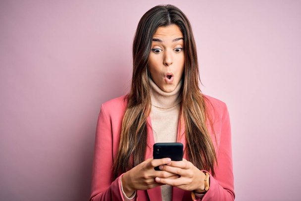 Young beautiful girl having conversation using smartphone over white background scared in shock with a surprise face, afraid and excited with fear expression - Φωτογραφία, εικόνα